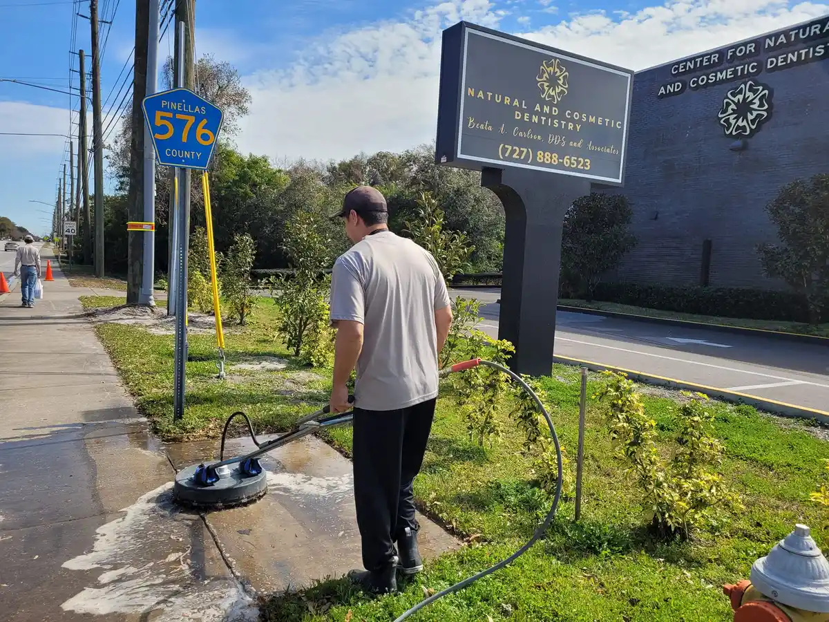 Brian Vasquez operating a commercial rotary surface cleaner with safety cones on a Clearwater Florida HOA boulevard sidewalk
