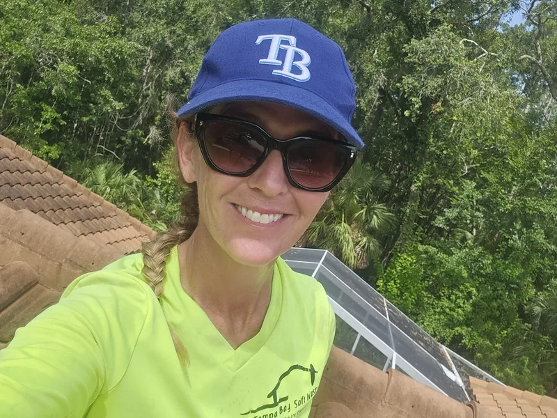 Jessica Lakins, Co-Owner, Field Operator, and Greenbrier Club HOA President cleaning gutters on a roof in Clearwater, FL