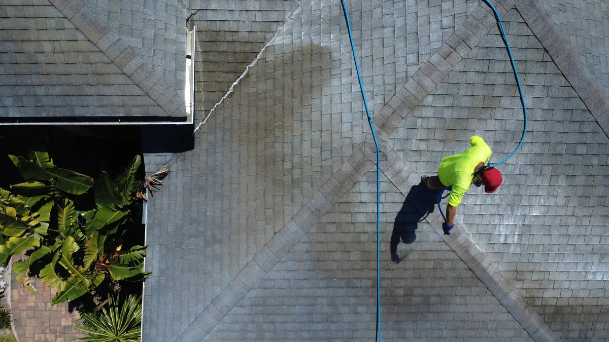Drone view of asphalt shingle roof cleaning in progress showing clean and dirty halves in Citrus Park FL