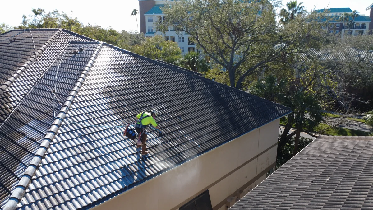Tampa Bay Soft Wash technician soft washing barrel tile roof with fall protection harness in Tampa Harbour Island