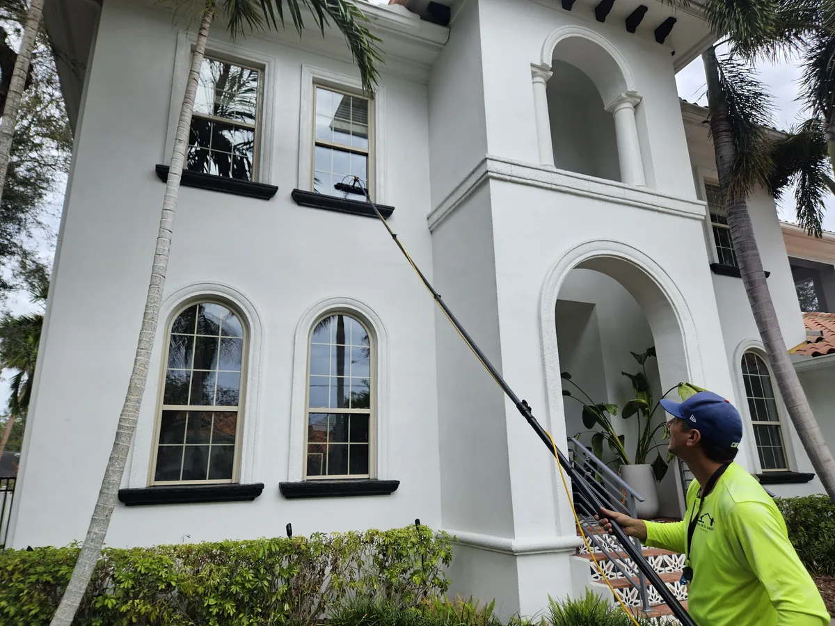 Technician cleaning residential windows using a pure water-fed pole system in Tampa Bay FL